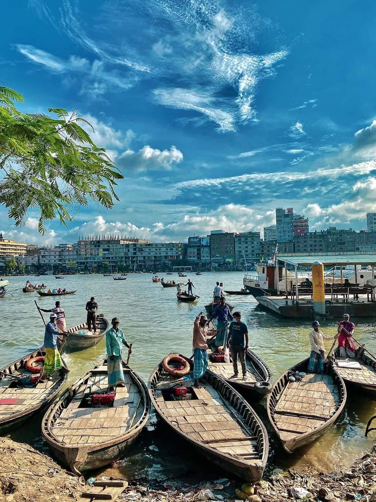 several small boats in the water with people standing on one side and another sitting on the other