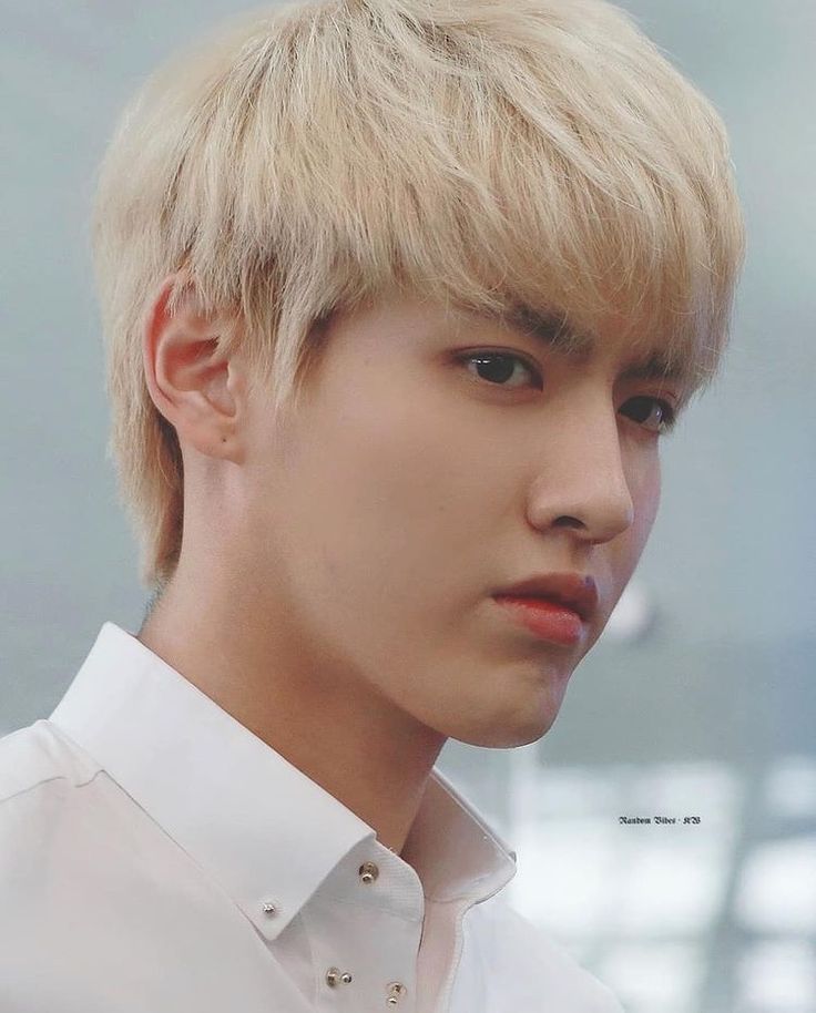 a close up of a person wearing a white shirt with blonde hair and blue eyes