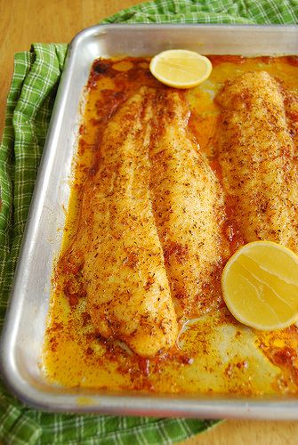 two fish fillets in a baking dish with lemons