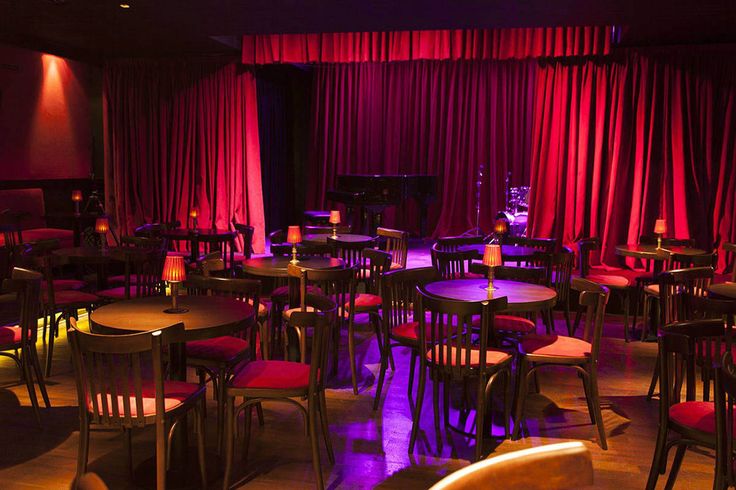 a dimly lit restaurant with red curtains and wooden tables