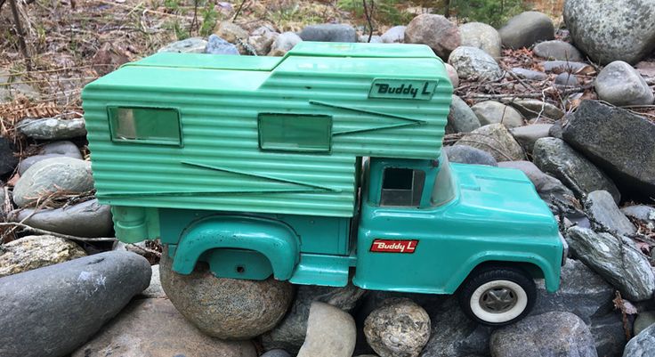 a toy truck is sitting on some rocks and gravel, with the trailer attached to it's back