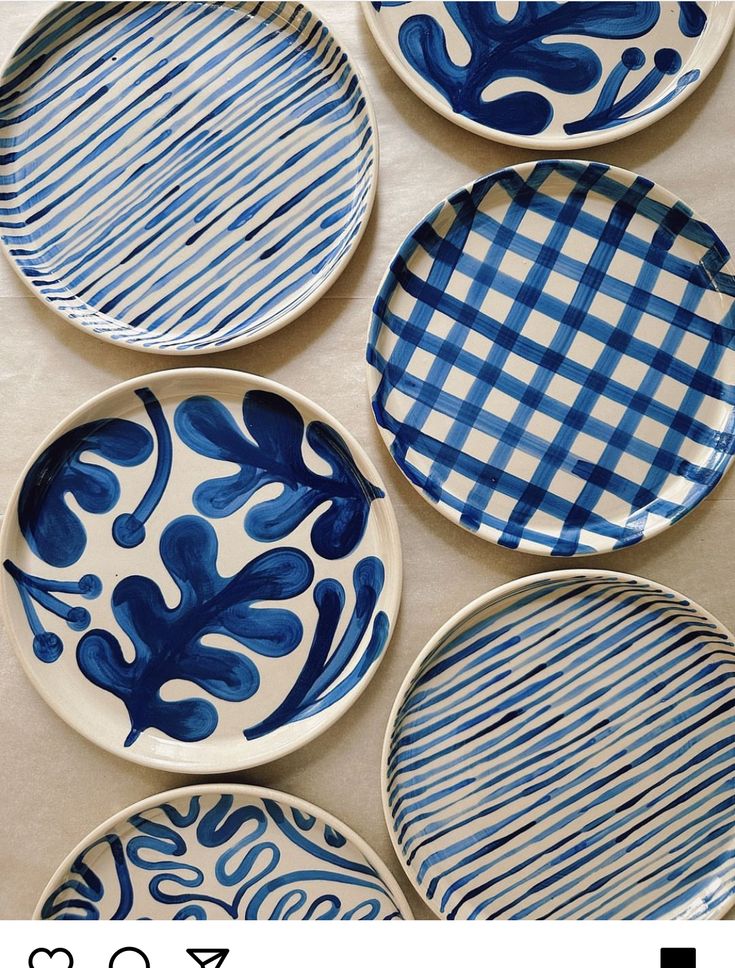 four blue and white plates sitting on top of a table next to eachother