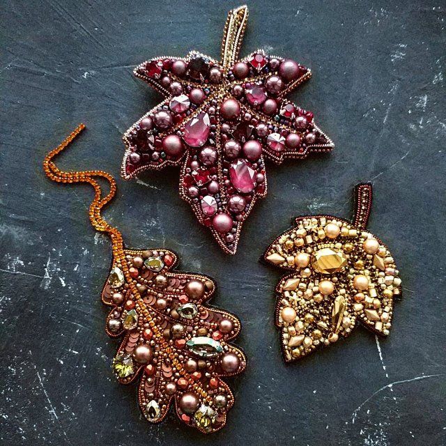 three pieces of beaded jewelry sitting on top of a black surface, one with an ornament and the other with beads