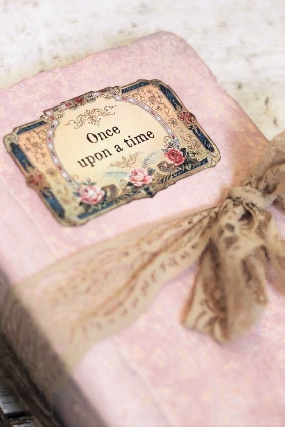 a pink gift box with an old fashioned label on it's lid and ribbon tied around the edge