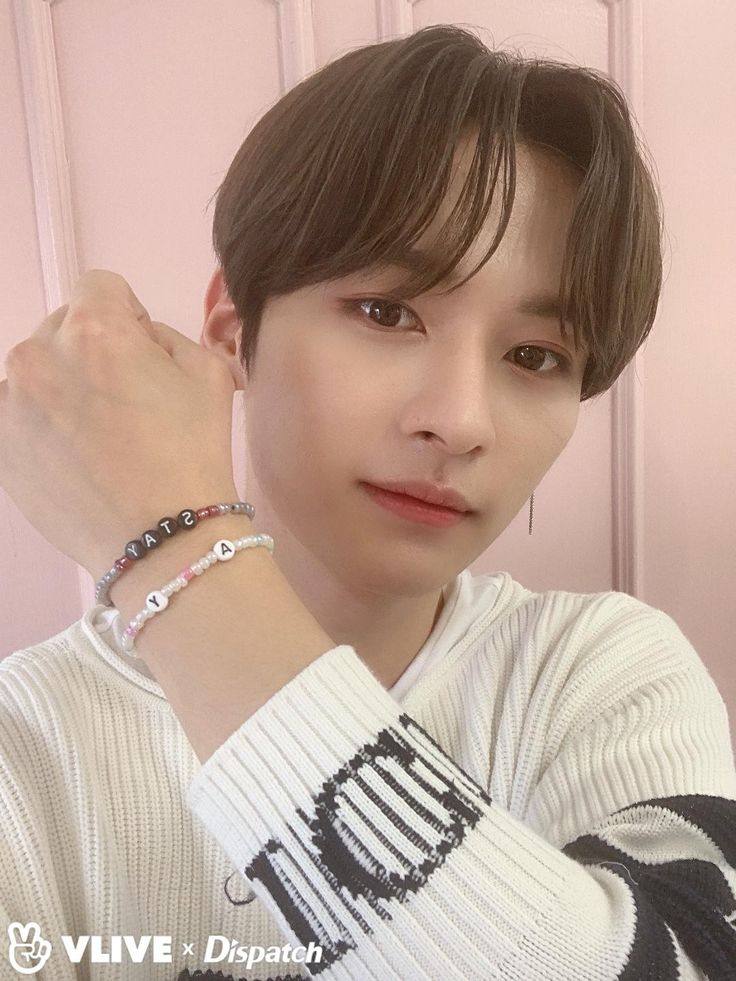 a young man wearing a white sweater and bracelet