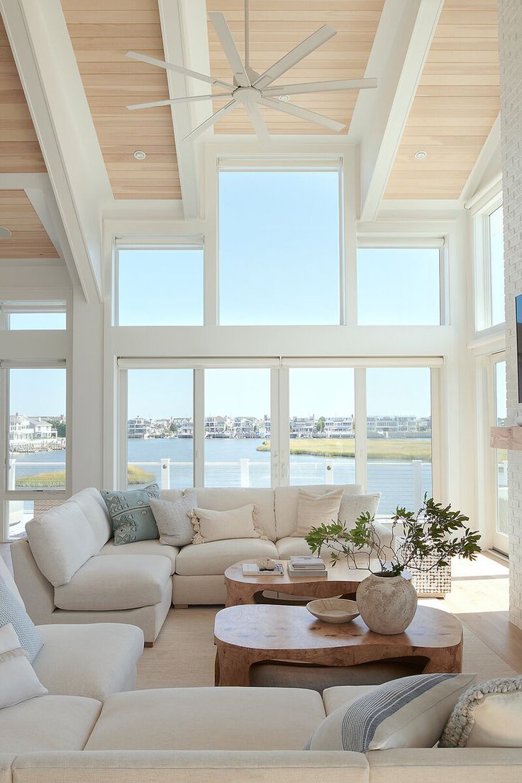 a living room filled with furniture and large windows overlooking the water on a sunny day