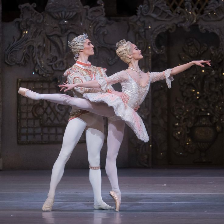 two ballerinas dressed in white and pink tutus, one holding the other's leg