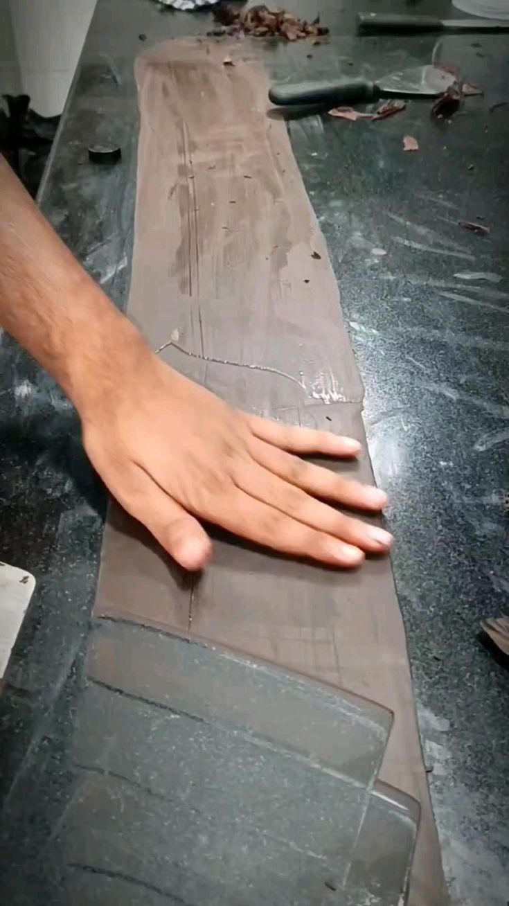 a person's hand on top of a piece of wood