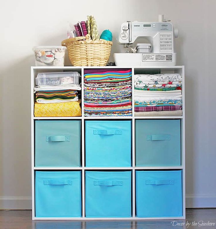 a white shelf filled with lots of different colored bins next to a sewing machine