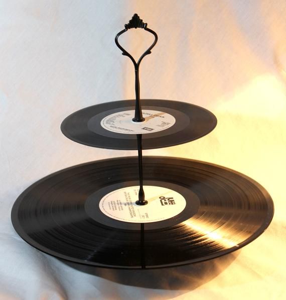 two black vinyl records stacked on top of each other with a metal stand holding them