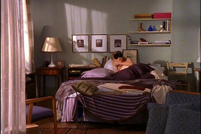 a man laying on top of a bed in a bedroom next to a desk and chair