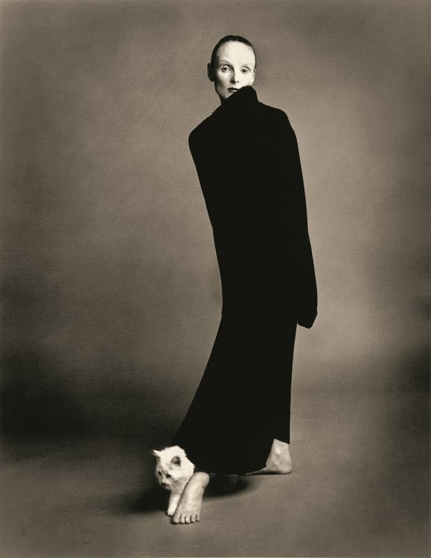 an old photo of a woman in black with a cat on her lap, posing for the camera