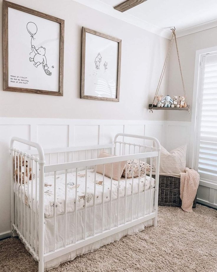 a white crib in a room with two pictures on the wall