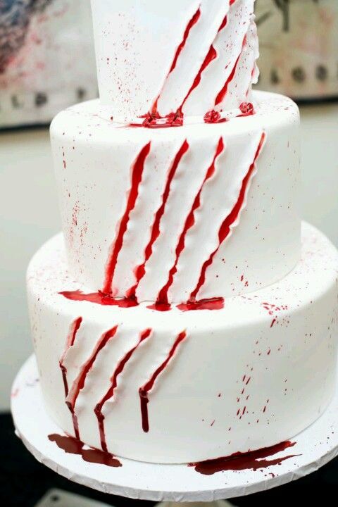 a three tiered white cake with red splatters on it