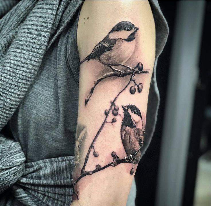 a bird on a branch with berries and leaves is shown in this tattoo artist's photo