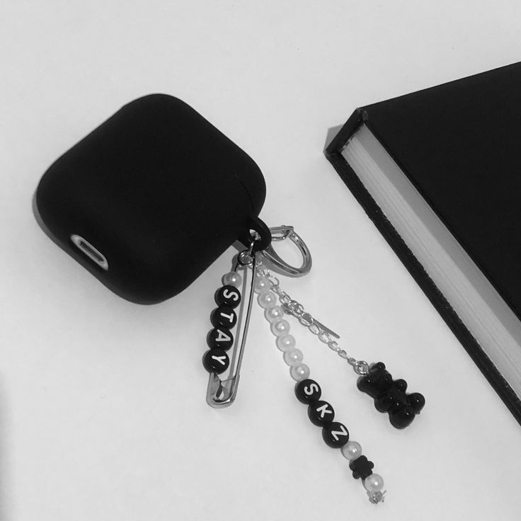 a black book and keychain sitting next to a pair of keys on a white surface