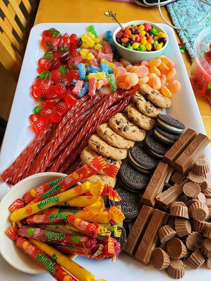 a table topped with lots of different types of candies and chocolates on top of white plates