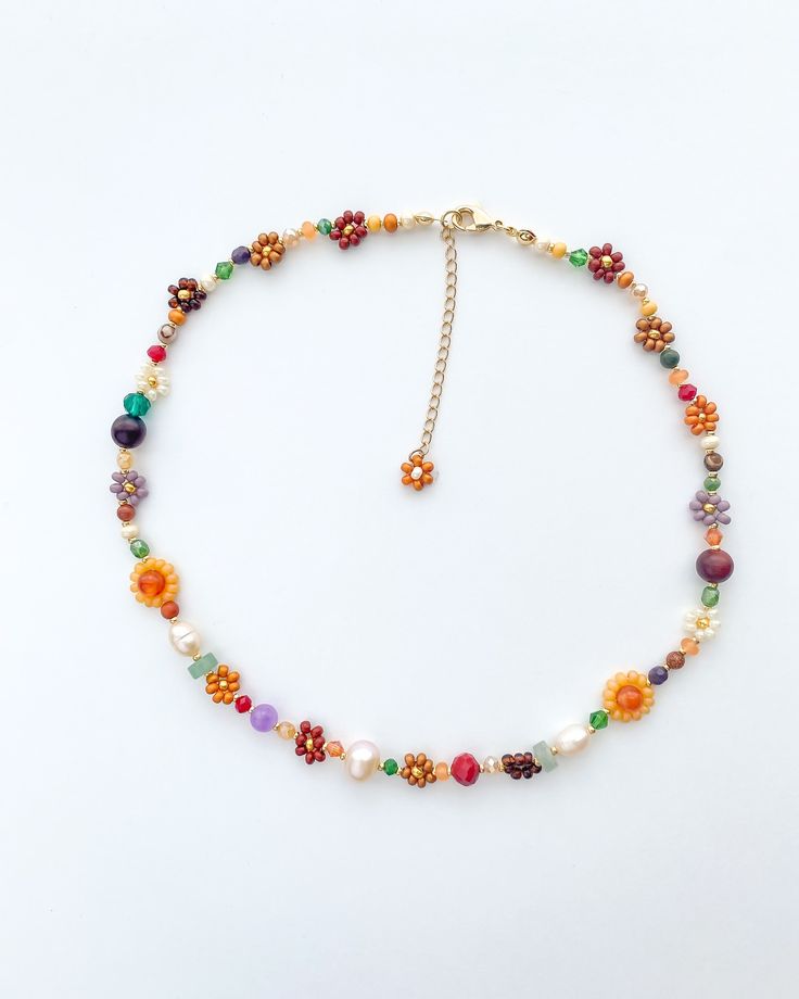 a multicolored beaded necklace is displayed on a white surface with a gold chain