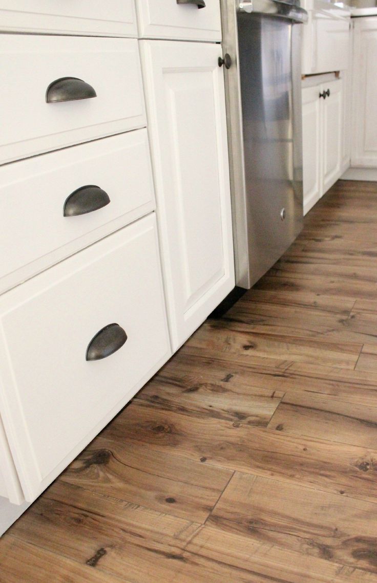 a kitchen with white cabinets and wood floors