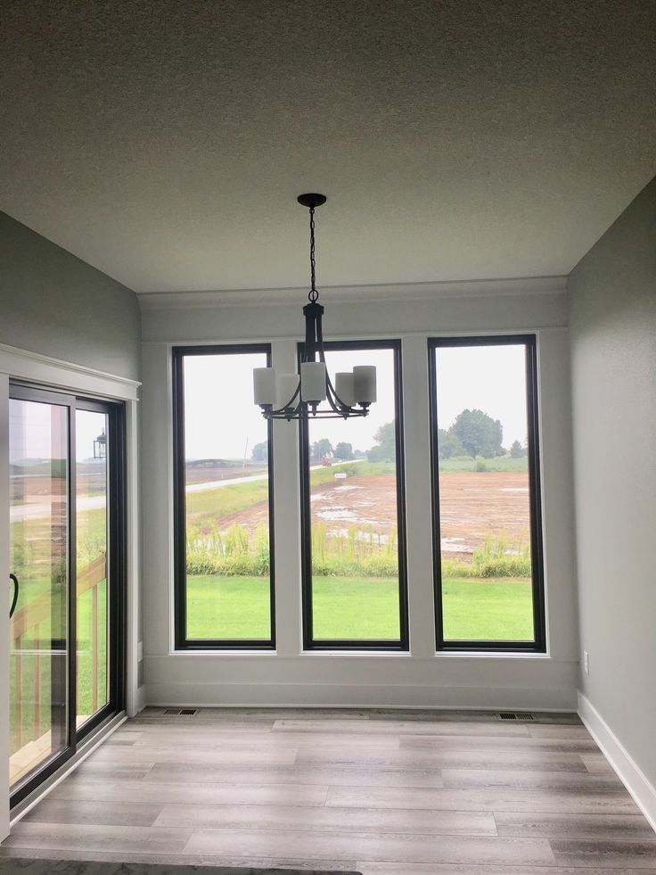 an empty room with three large windows and a chandelier hanging from the ceiling