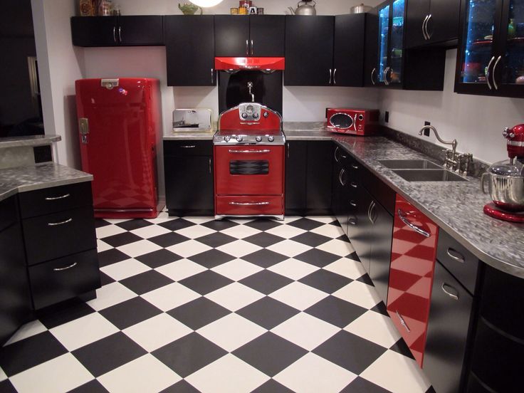 a black and white checkered floor in a kitchen with red appliances on the counters