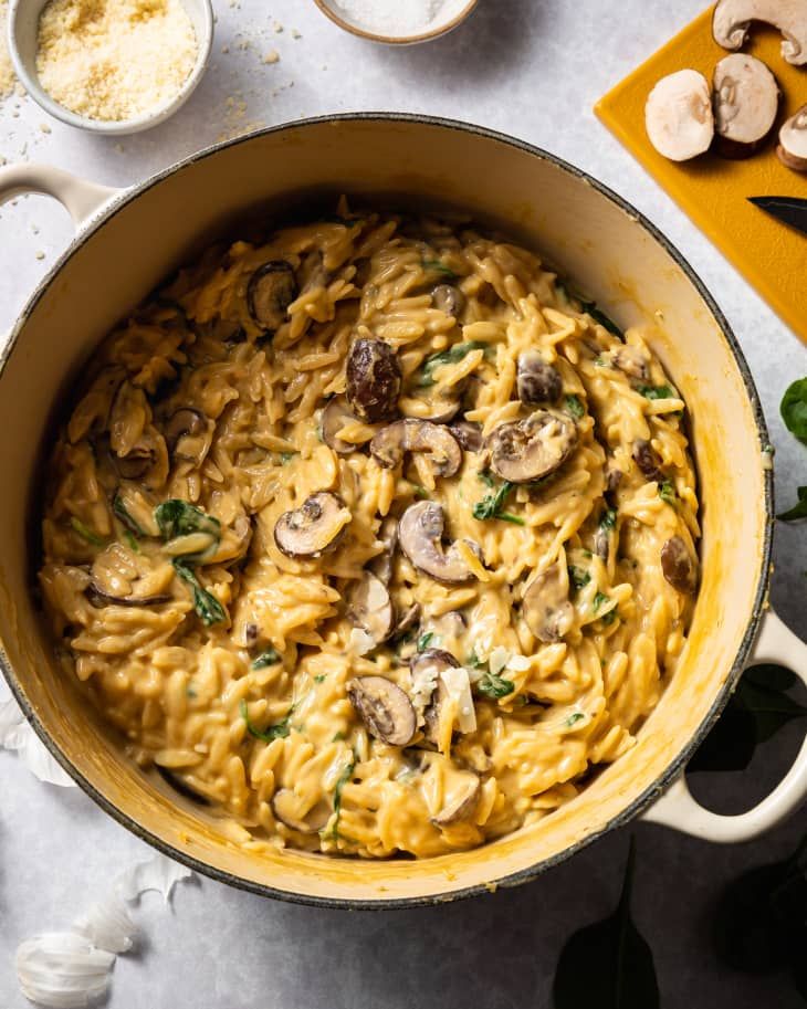 a pot filled with pasta and mushrooms on top of a table