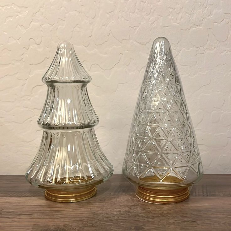 two clear glass vases sitting on top of a wooden table next to each other