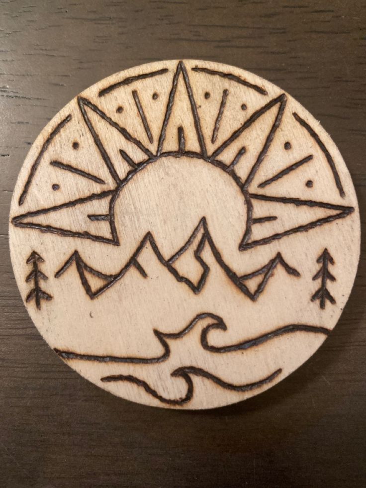 a wooden stamp with mountains and trees in the middle on a wood surface, which has been carved into a circle