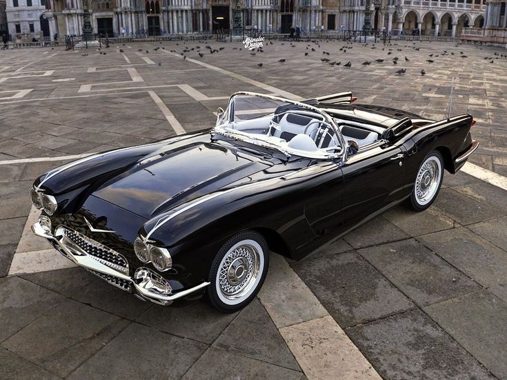 an old black convertible car parked in front of a building with pigeons on the ground