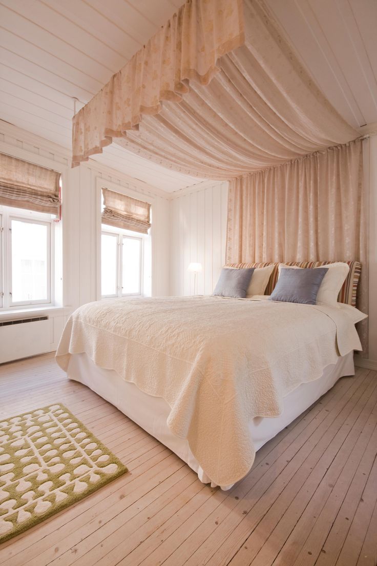 a large bed sitting in the middle of a bedroom next to a window with drapes