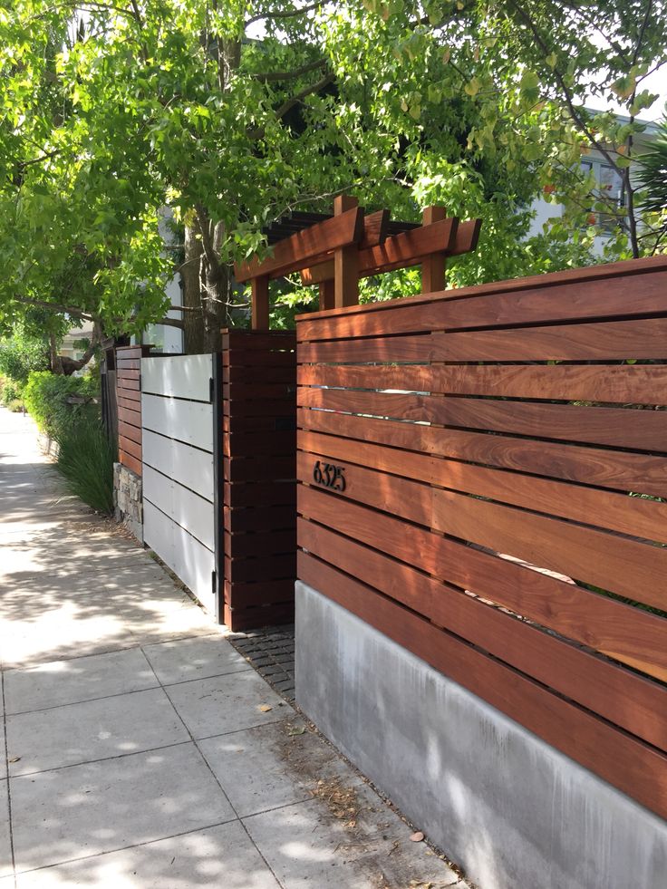 a wooden fence next to a sidewalk and trees