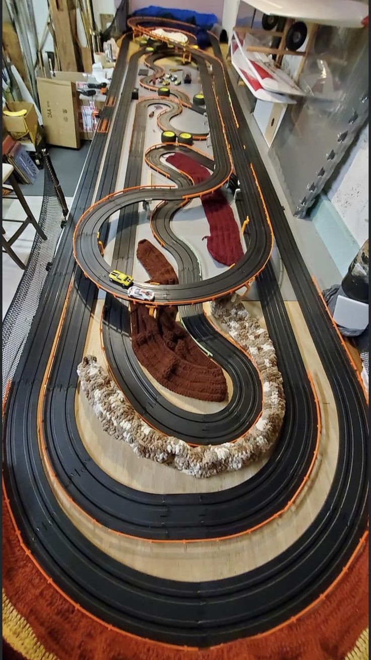 a model train track with multiple tracks and cars on it in a room filled with other items