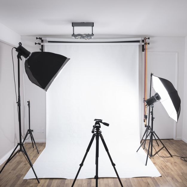 an empty photo studio with two lights and one tripod in front of the camera