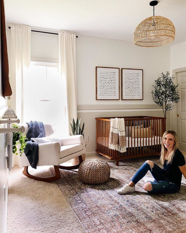 a woman sitting on the floor in front of a baby crib