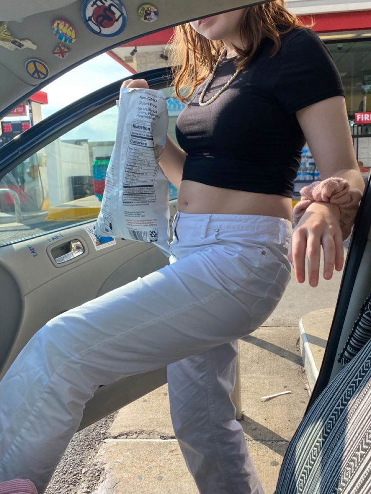 a woman is sitting in the back seat of a car and holding a water bottle