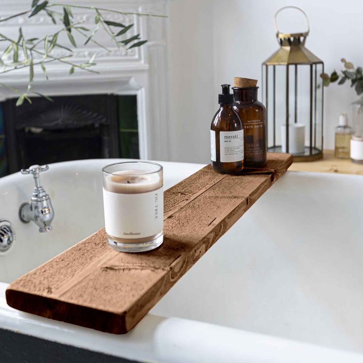 a candle and some bottles sitting on a bathtub ledge in a bathroom with a fireplace