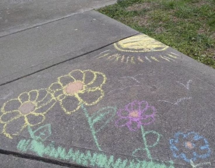 the sidewalk has flowers drawn on it and grass in the backgroung area