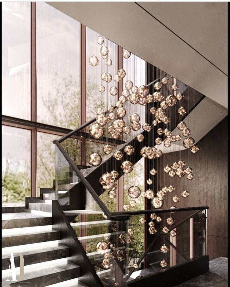 an artistic staircase with glass balls hanging from it's handrails in front of large windows