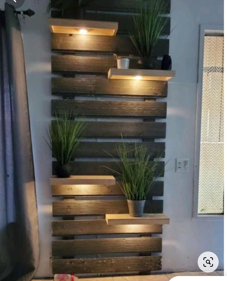 some potted plants are sitting on wooden shelves with lights in the middle of them