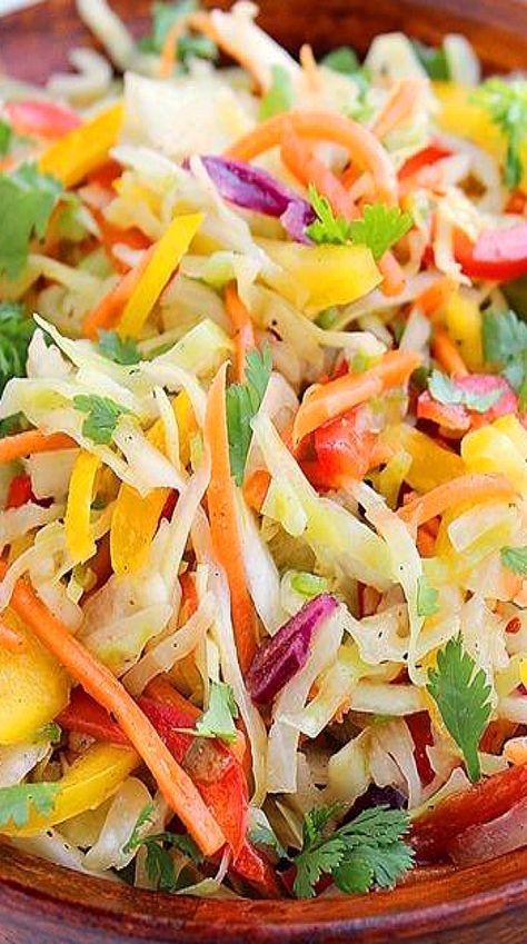 a wooden bowl filled with coleslaw salad and garnished with cilantro