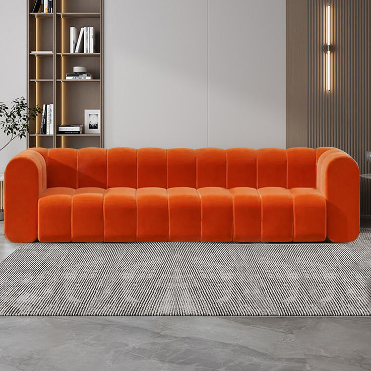 an orange couch sitting on top of a rug next to a book shelf filled with books