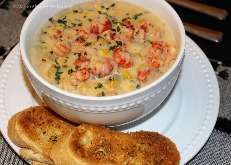 a white plate topped with a bowl of soup and two pieces of bread