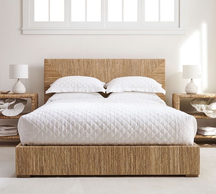 the bed is made up with white linens and wicker headboard, along with two nightstands