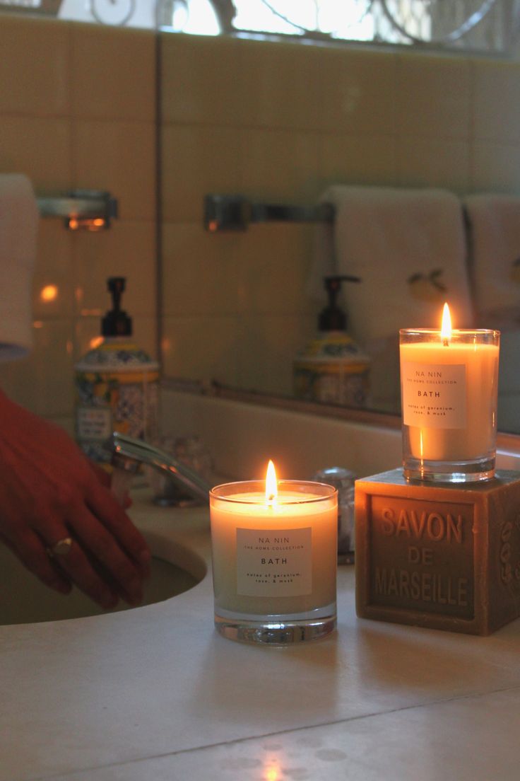 three candles sitting on top of a bathroom counter