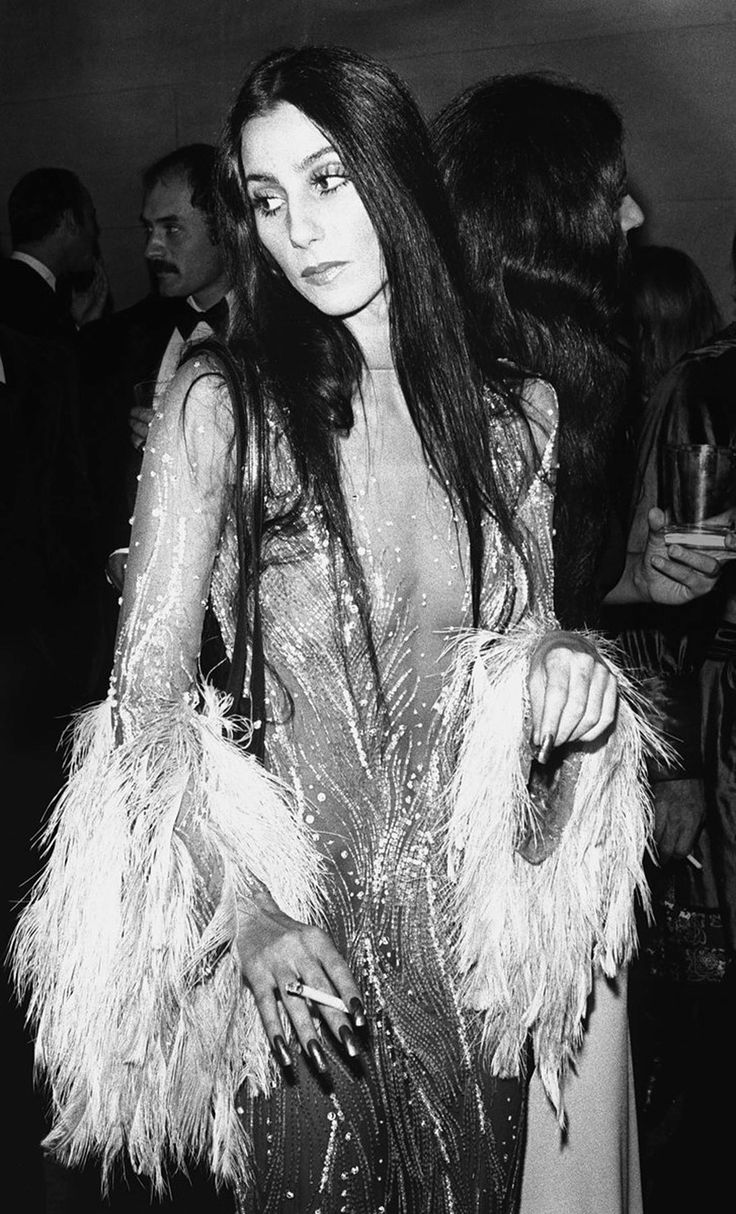 black and white photograph of a woman in a feathered dress at an event with other people