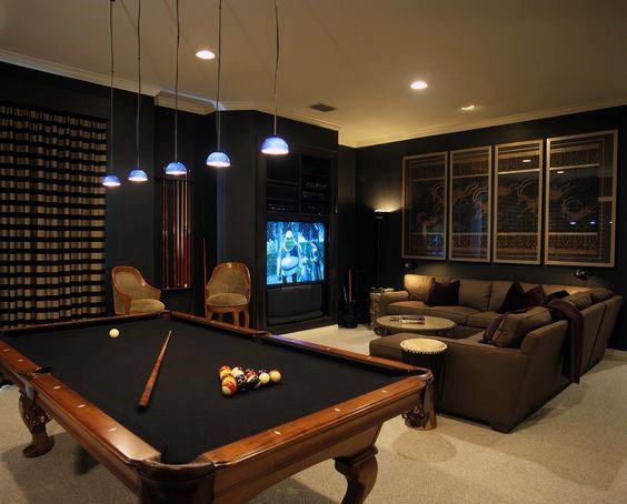 a living room with a pool table, couches and television in the corner on the wall