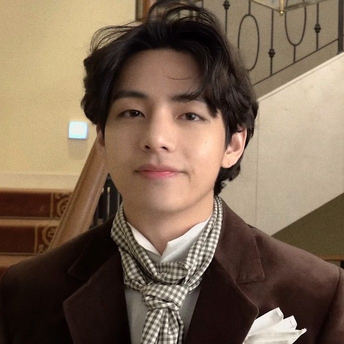 a young man wearing a suit and tie standing in front of some stairs with his hand on his hip