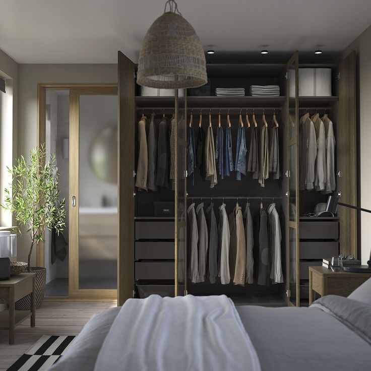 an open closet with clothes hanging on the wall and a bed in the foreground