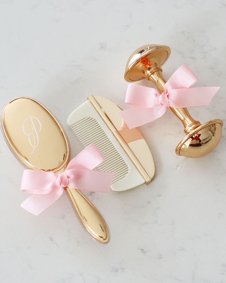 two personalized hair combs with pink bows and a monogrammed comb on a marble surface