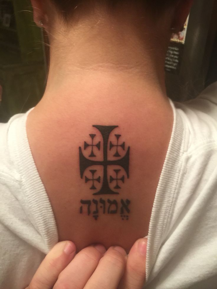 a woman with a cross tattoo on her upper back shoulder and hand in front of her chest